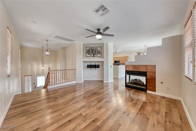 4044 Villeroy Ave, Las Vegas, NV 89141 - unfurnished living room featuring a tile fireplace, light wood finished floors, ceiling fan, and baseboards