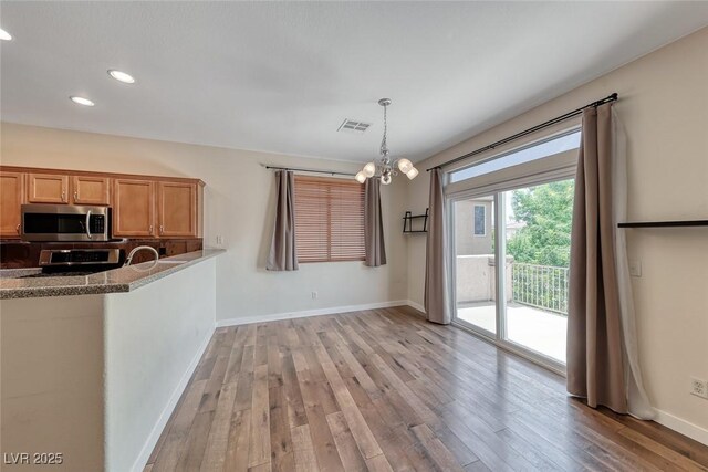 4044 Villeroy Ave, Las Vegas, NV 89141 - kitchen with stainless steel microwave, light wood-style floors, recessed lighting, a chandelier, and baseboards