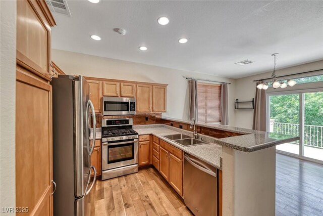 4044 Villeroy Ave, Las Vegas, NV 89141 - kitchen featuring appliances with stainless steel finishes, a sink, light wood-type flooring, a peninsula, and recessed lighting