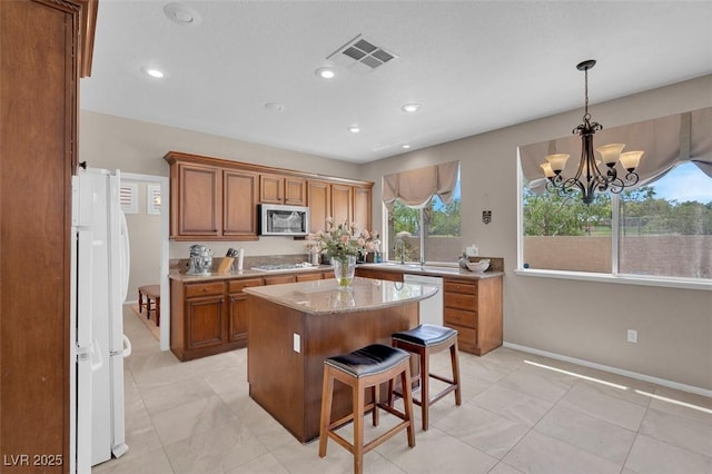 9017 Cotton Rose Way, Las Vegas, NV 89134 - kitchen with white appliances, brown cabinetry, a center island, a breakfast bar, and a chandelier
