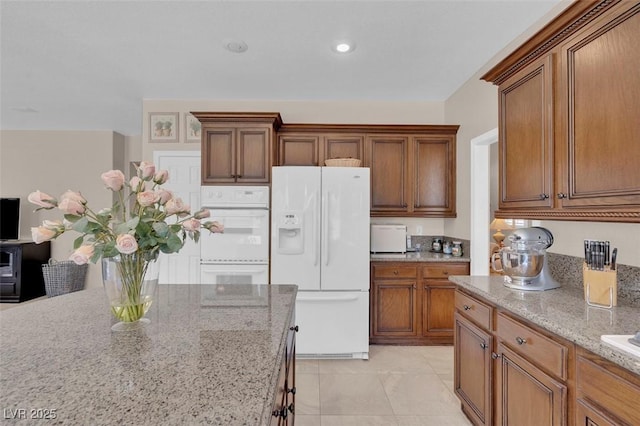 9017 Cotton Rose Way, Las Vegas, NV 89134 - kitchen with white appliances, light stone countertops, and brown cabinetry