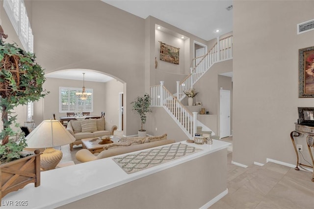 9017 Cotton Rose Way, Las Vegas, NV 89134 - living area featuring a high ceiling, arched walkways, stairway, baseboards, and a chandelier