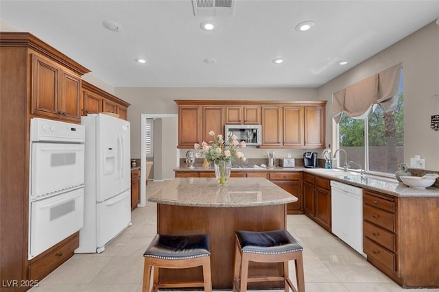 9017 Cotton Rose Way, Las Vegas, NV 89134 - kitchen with white appliances, a sink, a center island, brown cabinets, and recessed lighting