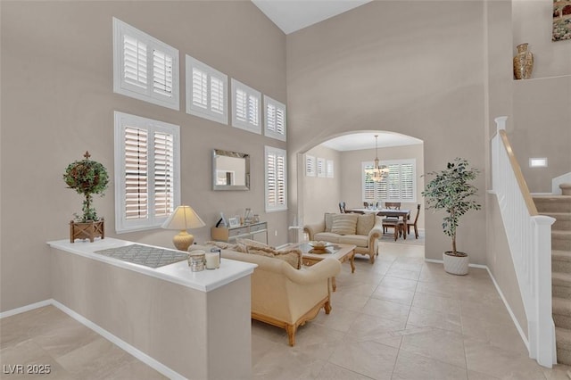 9017 Cotton Rose Way, Las Vegas, NV 89134 - living room featuring arched walkways, a high ceiling, stairway, baseboards, and a chandelier
