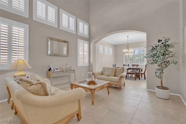 9017 Cotton Rose Way, Las Vegas, NV 89134 - living room with arched walkways, a chandelier, baseboards, a high ceiling, and light tile patterned floors