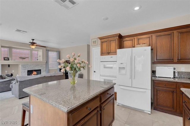 9017 Cotton Rose Way, Las Vegas, NV 89134 - kitchen featuring white appliances, light stone countertops, a stone fireplace, a ceiling fan, and a center island