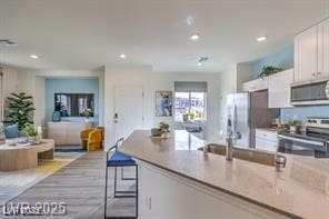 7915 Pandora Sky St Unit 402, North Las Vegas, NV 89084 - kitchen featuring stainless steel appliances, white cabinetry, open floor plan, recessed lighting, and light stone counters
