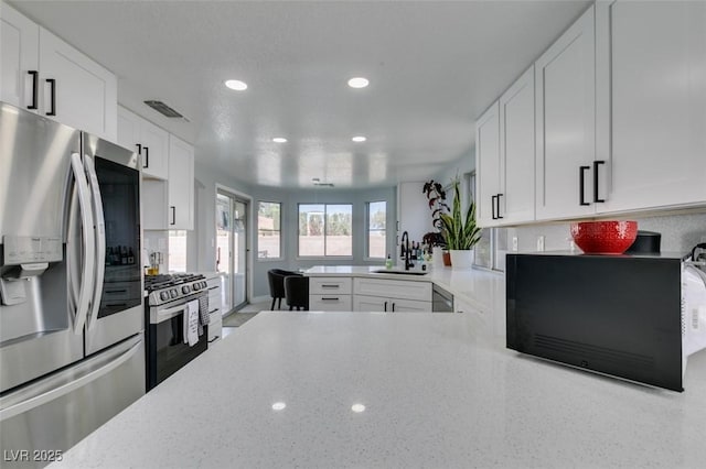 8150 Beaverbrook Way, Las Vegas, NV 89123 - kitchen with stainless steel appliances, a sink, recessed lighting, white cabinetry, and light stone countertops