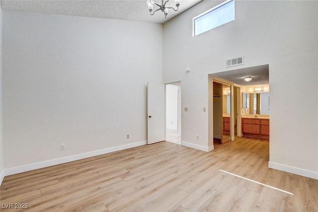 8233 Willeta Ave, Las Vegas, NV 89145 - unfurnished bedroom featuring a chandelier, wood finished floors, baseboards, ensuite bathroom, and a high ceiling