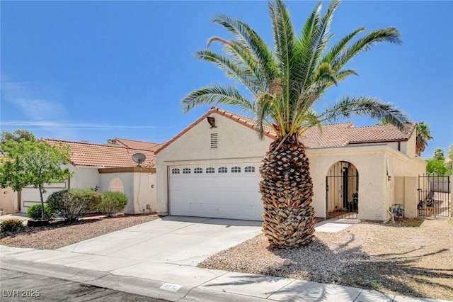 8233 Willeta Ave, Las Vegas, NV 89145 - mediterranean / spanish house featuring an attached garage, stucco siding, a tile roof, driveway, and a gate