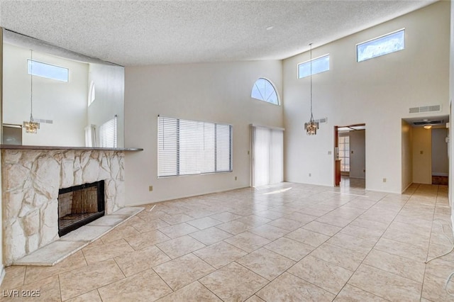 8233 Willeta Ave, Las Vegas, NV 89145 - unfurnished living room featuring a towering ceiling, a stone fireplace, a textured ceiling, plenty of natural light, and tile patterned floors