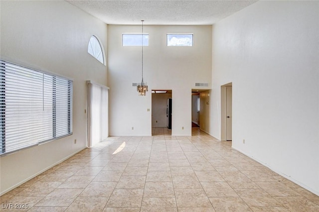 8233 Willeta Ave, Las Vegas, NV 89145 - unfurnished living room featuring a chandelier, a towering ceiling, a textured ceiling, and light tile patterned floors