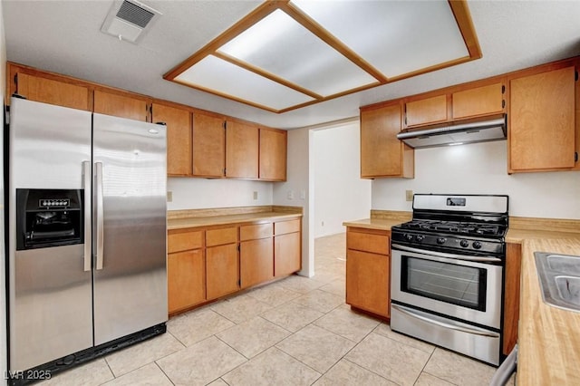 8233 Willeta Ave, Las Vegas, NV 89145 - kitchen featuring appliances with stainless steel finishes, under cabinet range hood, light countertops, light tile patterned floors, and brown cabinets