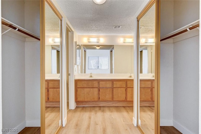 8233 Willeta Ave, Las Vegas, NV 89145 - full bathroom featuring double vanity, wood finished floors, a textured ceiling, and baseboards