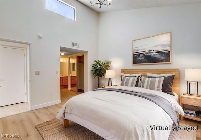 8233 Willeta Ave, Las Vegas, NV 89145 - bedroom featuring wood finished floors, baseboards, a towering ceiling, ensuite bathroom, and a chandelier