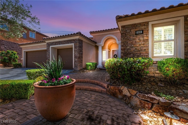900 Cantura Mills Rd, Henderson, NV 89052 - mediterranean / spanish home with stone siding, an attached garage, stucco siding, driveway, and a tile roof