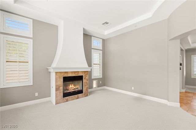 900 Cantura Mills Rd, Henderson, NV 89052 - unfurnished living room featuring a tiled fireplace, a tray ceiling, light carpet, and baseboards