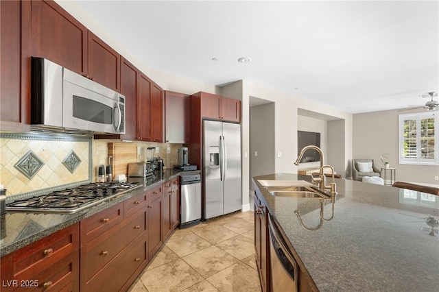 900 Cantura Mills Rd, Henderson, NV 89052 - kitchen featuring stainless steel appliances, dark brown cabinets, a sink, decorative backsplash, and ceiling fan
