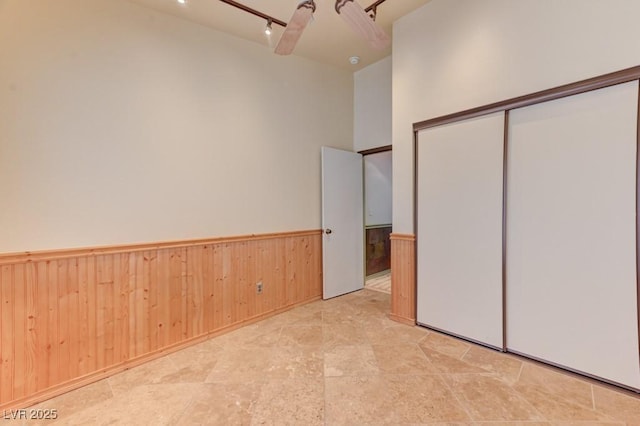 1523 Silver Point Ave, Las Vegas, NV 89123 - unfurnished bedroom with a wainscoted wall, wood walls, a closet, and rail lighting