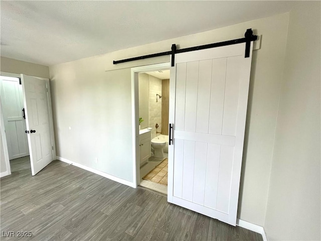 5191 Caliente St Unit 84, Las Vegas, NV 89119 - unfurnished bedroom with a barn door, wood finished floors, and baseboards