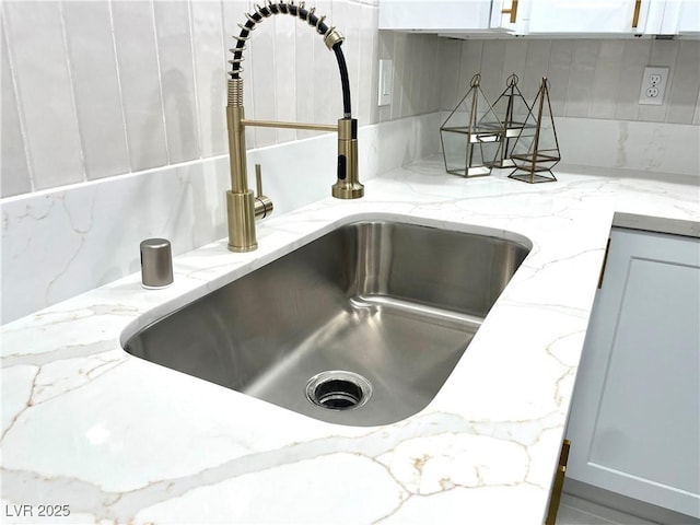 5191 Caliente St Unit 84, Las Vegas, NV 89119 - kitchen view of a sink, decorative backsplash, white cabinets, and light stone counters