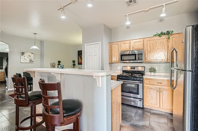 6321 Rolling Rose St Unit 201, North Las Vegas, NV 89081 - kitchen with appliances with stainless steel finishes, rail lighting, light countertops, light brown cabinets, and a breakfast bar