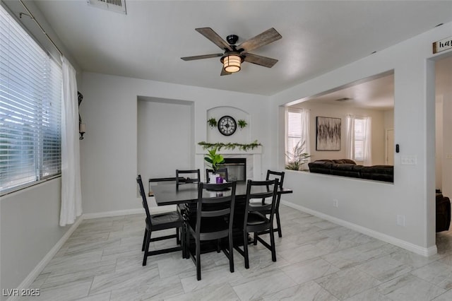 11004 Napa Ridge Dr, Las Vegas, NV 89144 - dining area with a ceiling fan, a glass covered fireplace, plenty of natural light, and baseboards