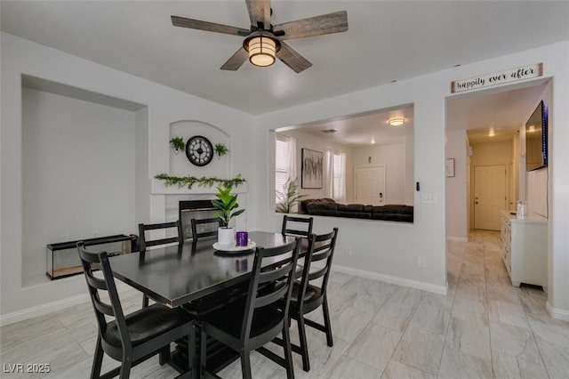 11004 Napa Ridge Dr, Las Vegas, NV 89144 - dining space featuring a glass covered fireplace, ceiling fan, and baseboards