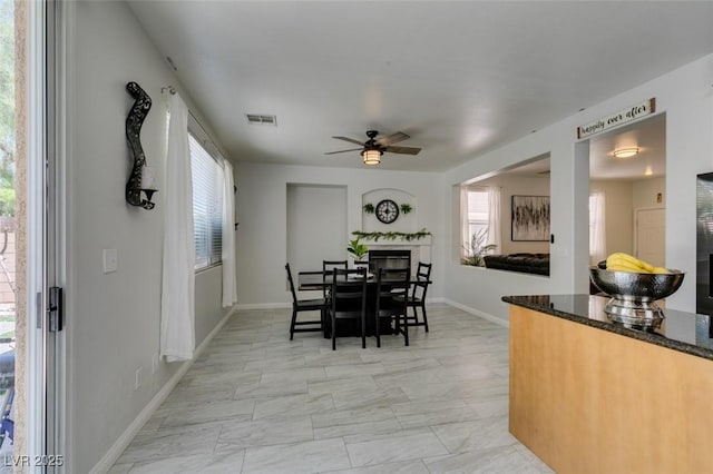 11004 Napa Ridge Dr, Las Vegas, NV 89144 - dining room featuring ceiling fan, healthy amount of natural light, a glass covered fireplace, and baseboards