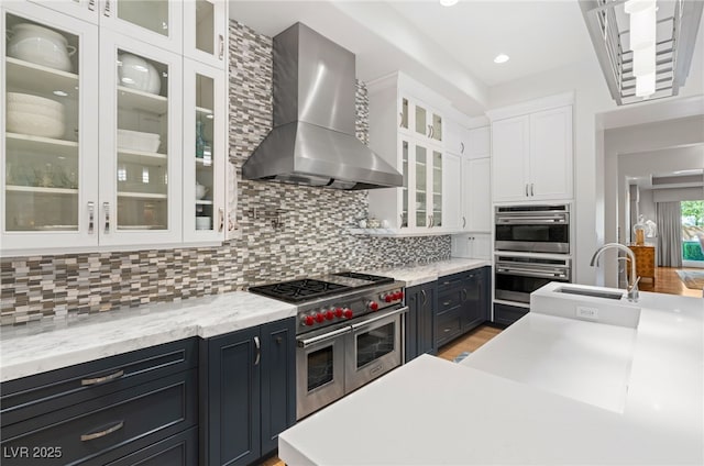 11 Misty Peaks Ct, Las Vegas, NV 89135 - kitchen with wall chimney exhaust hood, appliances with stainless steel finishes, white cabinetry, light countertops, and decorative backsplash