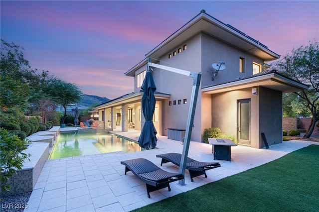 11 Misty Peaks Ct, Las Vegas, NV 89135 - back of house at dusk featuring stucco siding, a patio area, an outdoor pool, and a lawn