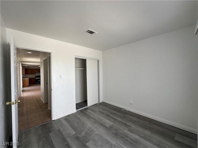6905 Singing Dunes Ln, Las Vegas, NV 89145 - unfurnished bedroom with dark wood-style floors, a closet, and baseboards