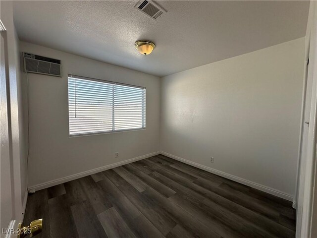 6905 Singing Dunes Ln, Las Vegas, NV 89145 - spare room with a wall mounted air conditioner, dark wood-style floors, baseboards, and a textured ceiling