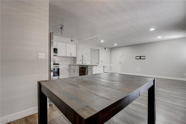 7905 Idledale Ct Unit 102, Las Vegas, NV 89145 - kitchen featuring baseboards, a textured ceiling, appliances with stainless steel finishes, white cabinetry, and light countertops