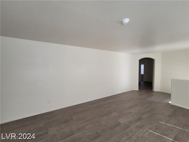 2711 Morning Break Ct, Las Vegas, NV 89142 - unfurnished living room featuring arched walkways, dark wood-style floors, and baseboards