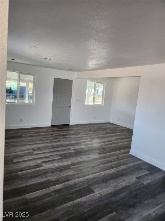 4231 E Kellogg Rd, Pahrump, NV 89061 - unfurnished room featuring baseboards, dark wood-style flooring, and a textured ceiling