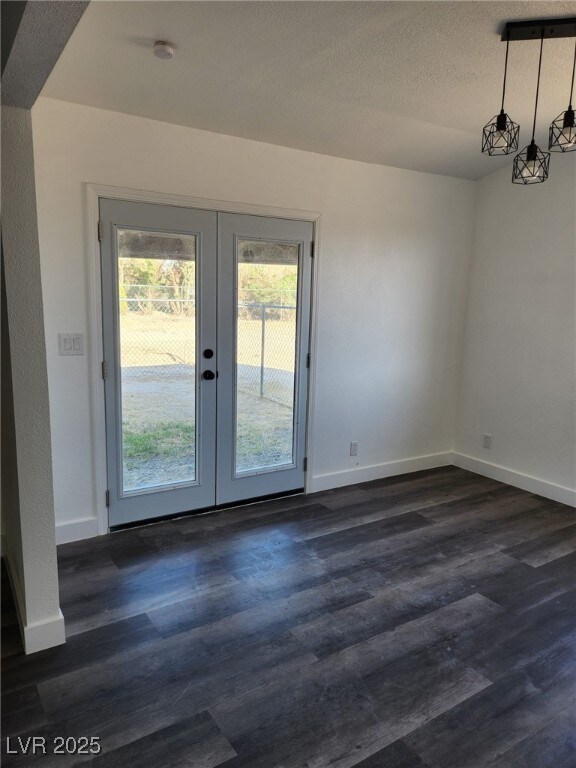 4231 E Kellogg Rd, Pahrump, NV 89061 - unfurnished room featuring french doors, dark wood-type flooring, baseboards, and a textured ceiling