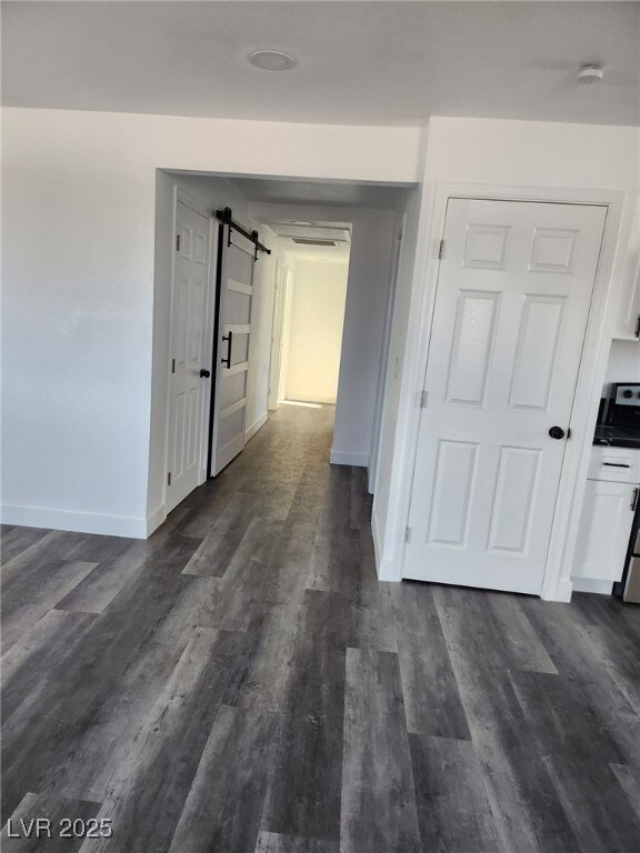 4231 E Kellogg Rd, Pahrump, NV 89061 - hallway with a barn door, baseboards, and dark wood-style flooring