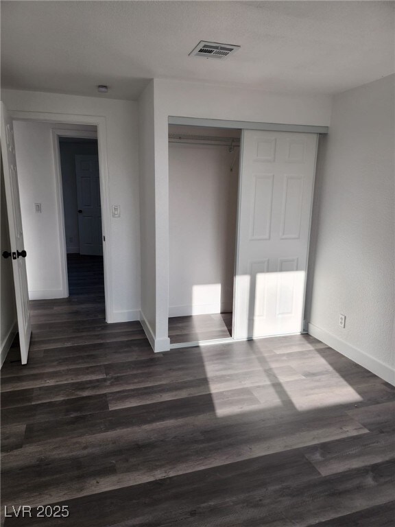 4231 E Kellogg Rd, Pahrump, NV 89061 - unfurnished bedroom with baseboards, a closet, and dark wood finished floors