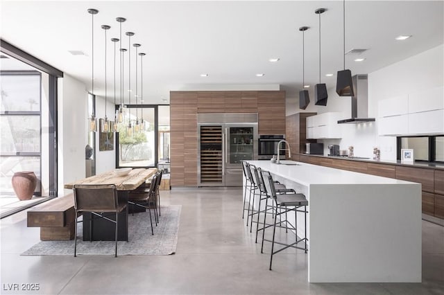 7030 Schirlls St, Las Vegas, NV 89118 - kitchen featuring modern cabinets, wall chimney range hood, stainless steel oven, a sink, and a kitchen bar