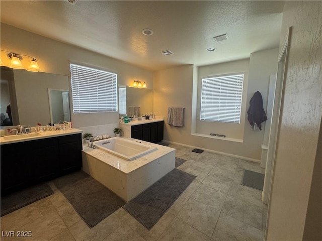 933 Kimbark Ave, Las Vegas, NV 89148 - bathroom featuring a bath, healthy amount of natural light, two vanities, a textured ceiling, and tile patterned floors