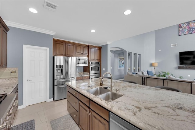 8268 Nelson Ridge Ln, Las Vegas, NV 89178 - kitchen with stainless steel appliances, a sink, arched walkways, light stone countertops, and ornamental molding