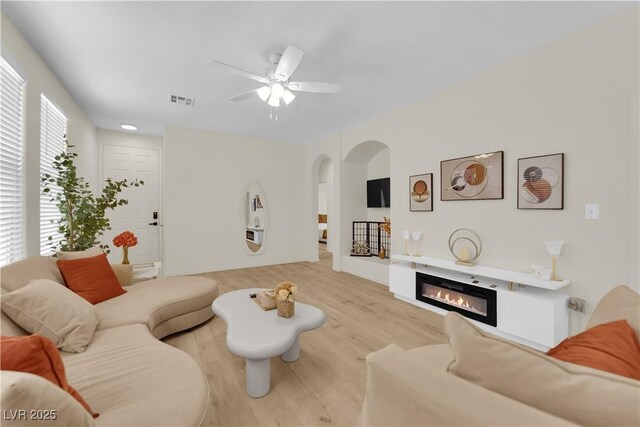 2633 Spider Cactus Ct, Las Vegas, NV 89106 - living room with arched walkways, a ceiling fan, wood finished floors, and a glass covered fireplace