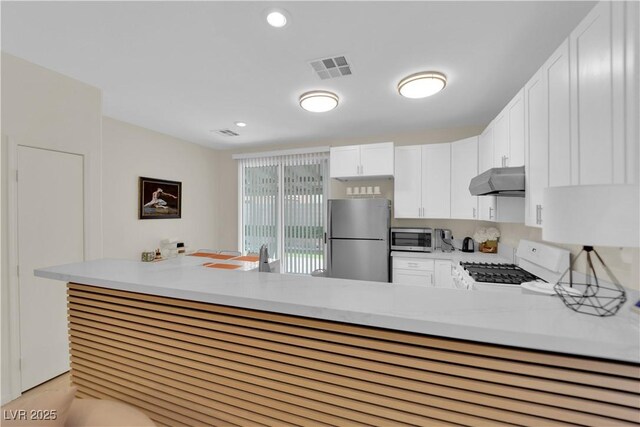 2633 Spider Cactus Ct, Las Vegas, NV 89106 - kitchen with appliances with stainless steel finishes, ventilation hood, white cabinets, light countertops, and a peninsula