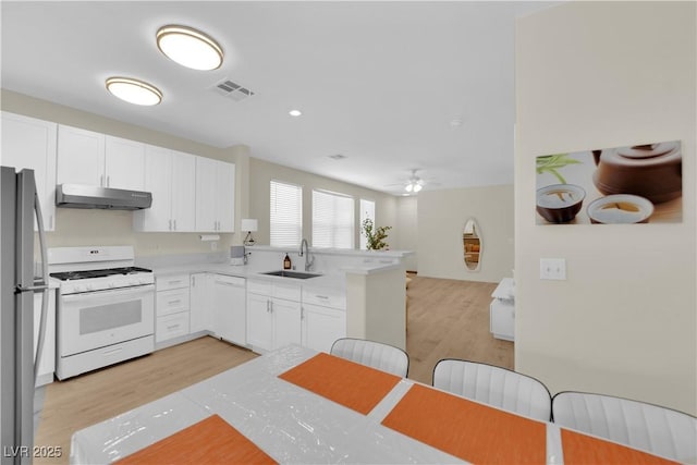 2633 Spider Cactus Ct, Las Vegas, NV 89106 - kitchen featuring white appliances, under cabinet range hood, a sink, light wood finished floors, and white cabinets