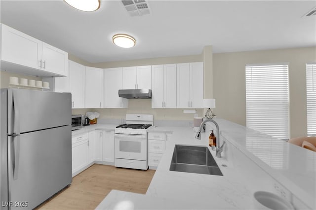 2633 Spider Cactus Ct, Las Vegas, NV 89106 - kitchen with appliances with stainless steel finishes, a sink, under cabinet range hood, light wood-style floors, and white cabinetry