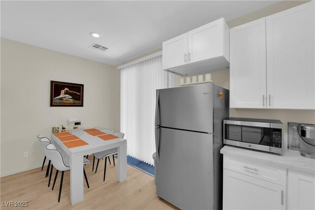 2633 Spider Cactus Ct, Las Vegas, NV 89106 - kitchen with appliances with stainless steel finishes, white cabinets, light wood-style floors, light stone countertops, and recessed lighting