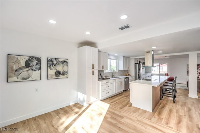 1731 Sherwin Ln, Las Vegas, NV 89156 - kitchen featuring island exhaust hood, stainless steel appliances, a breakfast bar area, recessed lighting, and light countertops
