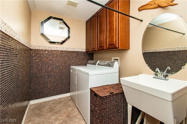 10798 Tapestry Winds St, Las Vegas, NV 89141 - washroom with separate washer and dryer, cabinet space, light tile patterned floors, a wainscoted wall, and tile walls