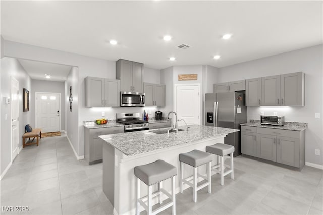 10951 Stone Crossing Ave, Las Vegas, NV 89166 - kitchen featuring appliances with stainless steel finishes, gray cabinetry, a sink, a kitchen bar, and baseboards